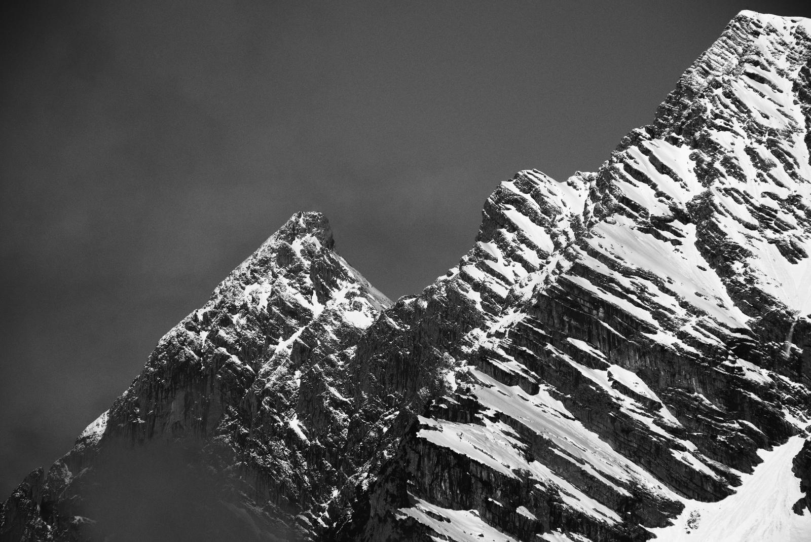 English:  A rugged ridge seen from the side, in places very bright. Clouds behind it. The photograph is in black and white. 

Deutsch: Ein schroffer Grat von der Seite, teilweise sehr hell. Dahinter Wolken. Das Foto ist in schwarzweiß.